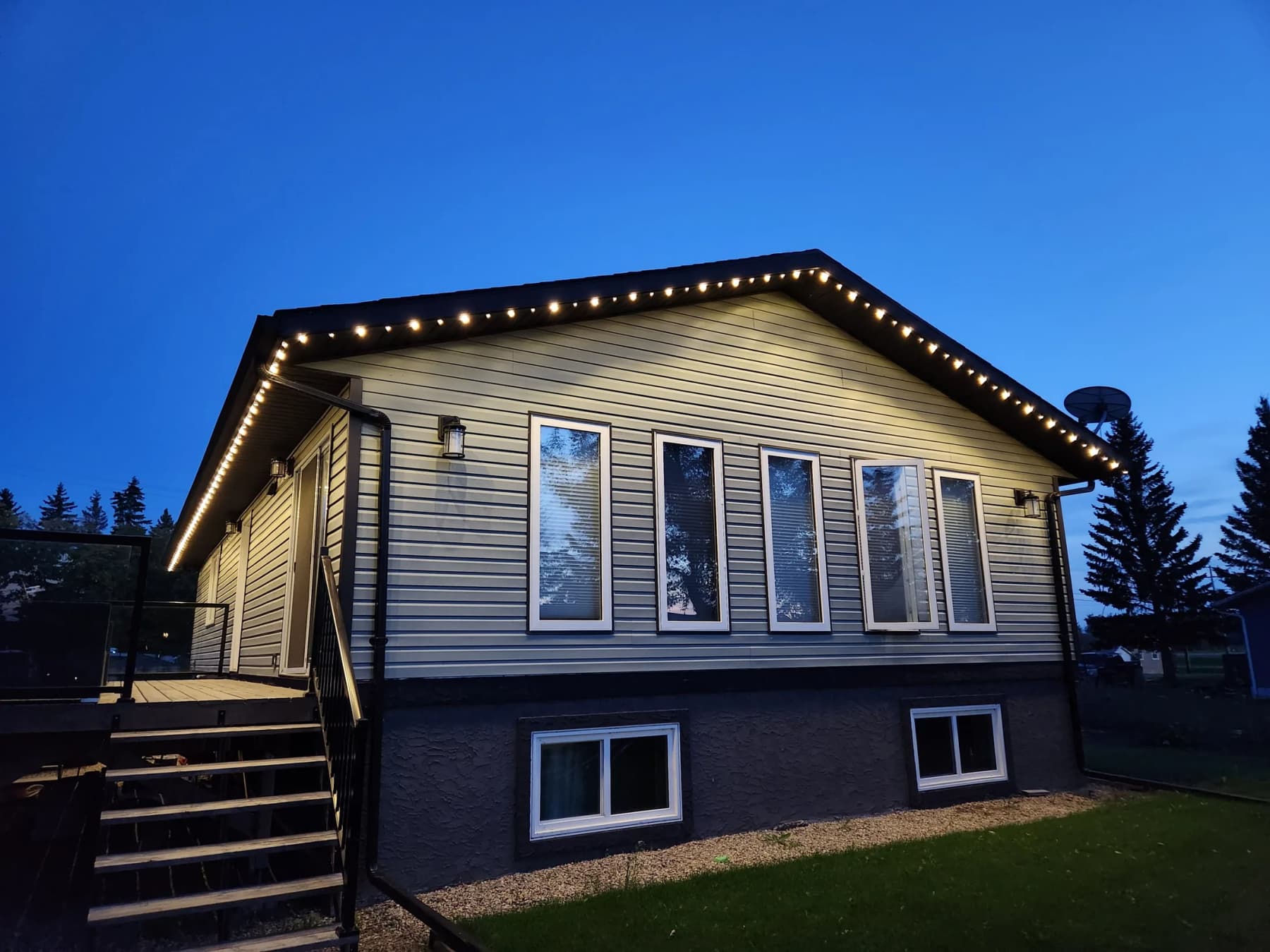 Home outlined in warm-white permanent LED track lighting at twilight