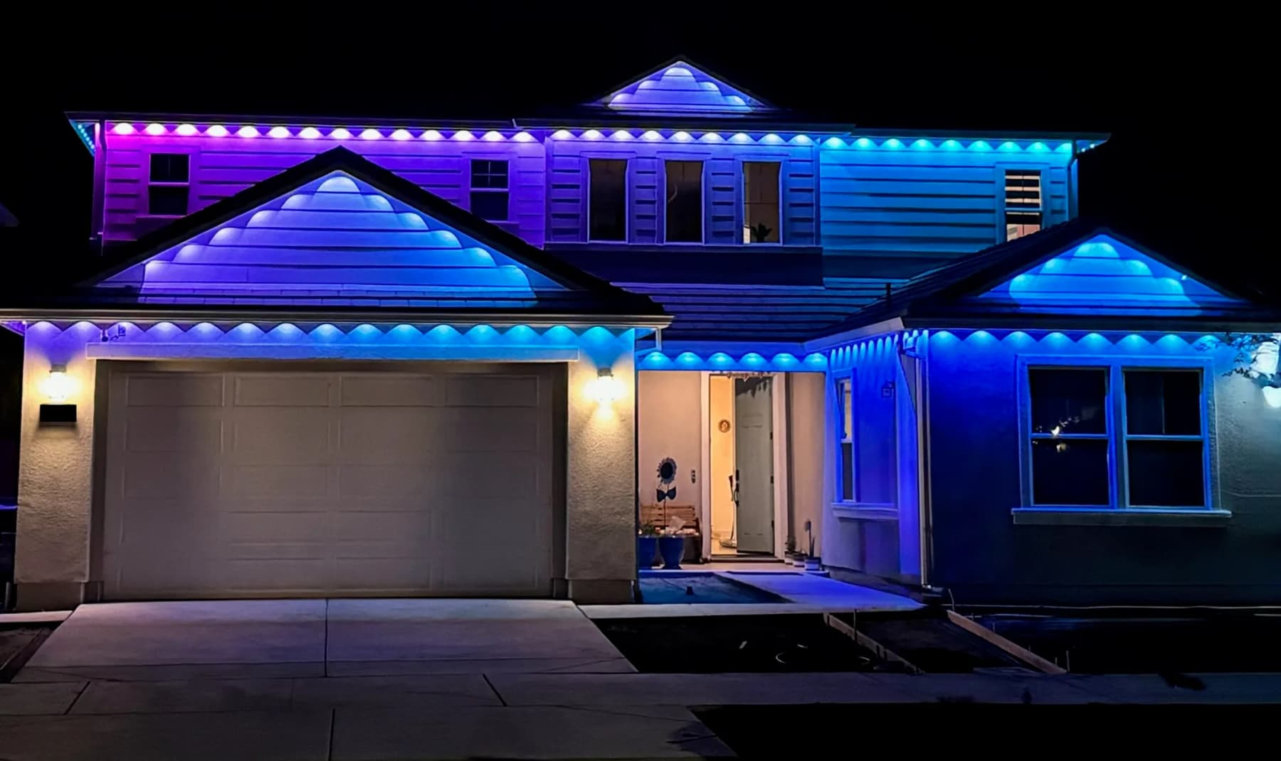 Wide building elevation lit end to end with soffit LED track lighting at night