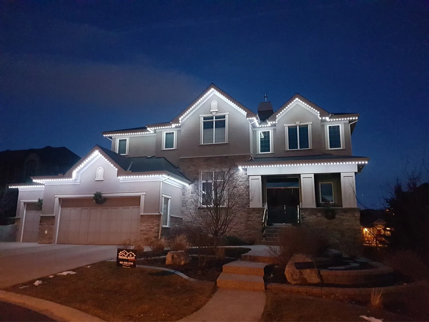 Dusk photo of a home with warm white permanent LED soffit lighting installed along the roofline, illustrating curb appeal for a resale value discussion